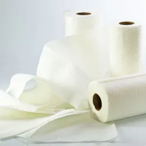Several rolls of white paper towels are arranged on a reflective surface.